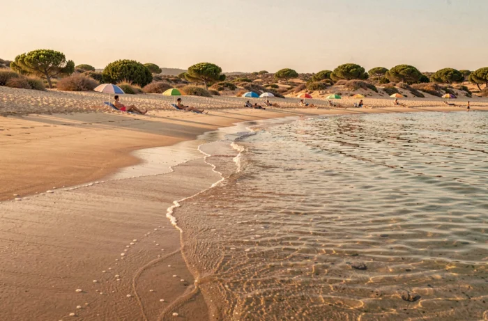 Plage de sable méditerranéenne ensoleillée proche de Nîmes avec parasols colorés et baigneurs au bord de l'eau en été