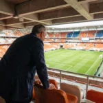 Vue panoramique depuis les tribunes supérieures du Groupama Stadium avec un spectateur observant le terrain de football